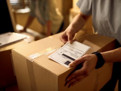 Close-up of courier attaching address label on a package while working in the office.
